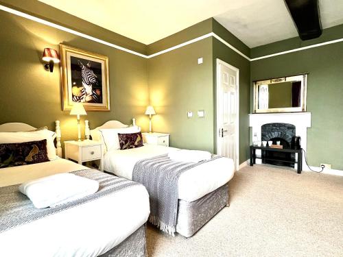 萨彻姆Colthrop Manor B&B的一间卧室设有两张床和一个壁炉