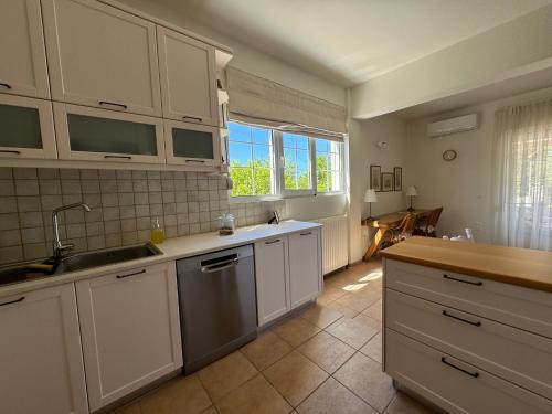 干尼亚Primavera Retreat的厨房配有白色橱柜、水槽和窗户。