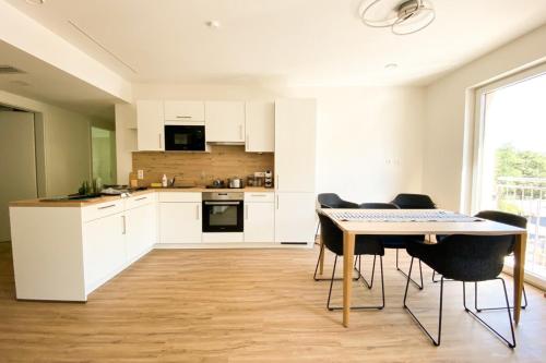 博福特230 Lux Furnished flat的厨房配有白色橱柜和桌椅