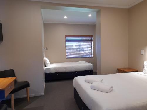 图朗伊Tongariro Junction Accommodation的酒店客房设有两张床和窗户。