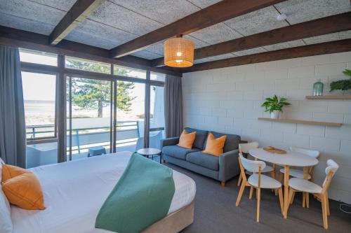 吉斯伯恩花落金沙海滨汽车旅馆 的一间卧室配有一张床、一张桌子和一张沙发