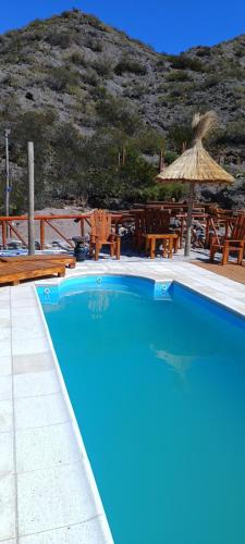波特雷里约斯Cabaña Rincón del Sol的蓝色的游泳池,配有草伞和椅子