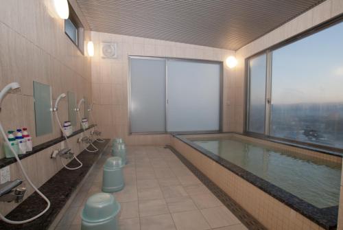 大村市Omura Station Hotel的一间带大窗户的游泳池的浴室