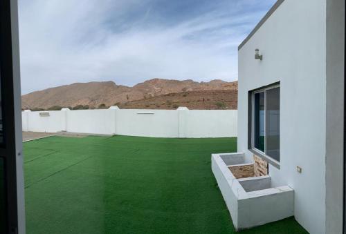 Ibrāبيت الضيافه للتواصل:98423336的沙漠中一片绿色草坪的房子