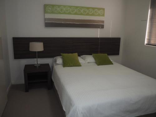 曼哲拉Lovely 2 Bedroom Serviced Apartment & Free Parking的卧室配有带绿色枕头的大型白色床
