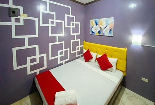 TagumRedDoorz at Queens Hometel的一间卧室配有红色和黄色枕头的床
