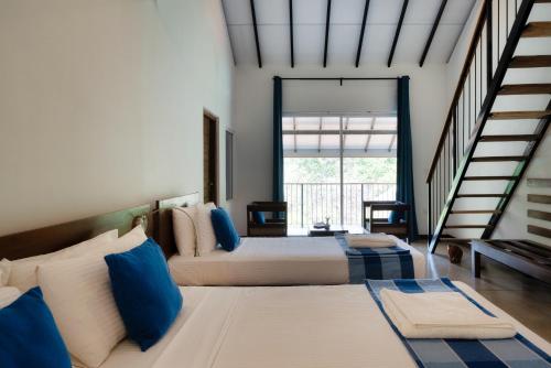 锡吉里亚Lario Resort Sigiriya的一间卧室配有两张带蓝白色枕头的床