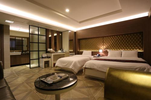 富川市齐尼思酒店的大型酒店客房设有两张床和一张桌子。