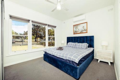 West Richmond6 BR House Near Adelaide Airport的一间卧室设有蓝色的床和窗户。