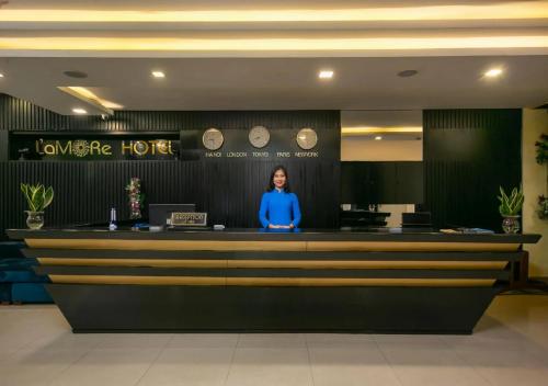 岘港L'emore Hotel Da Nang的站在酒店柜台的女人