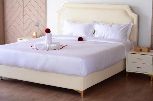 奈瓦沙THE ARK PARADIO LODGE的一间卧室配有一张白色的床,上面有两朵玫瑰花