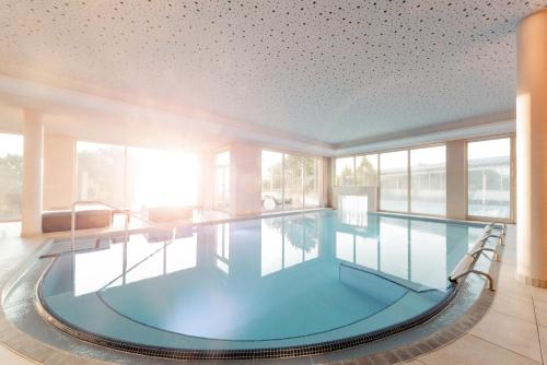 巴特塔茨曼斯多夫Avita Resort Bad Tatzmannsdorf的一座大型游泳池,位于一座带窗户的建筑内