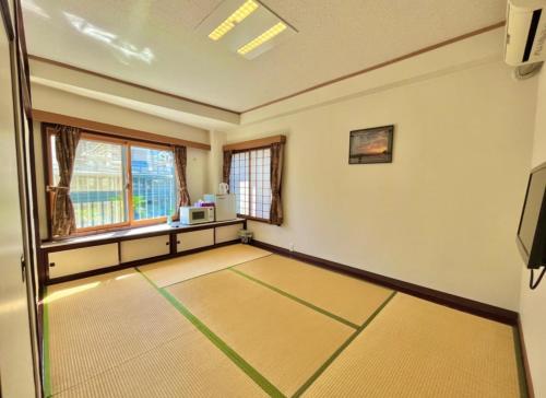 热海Hostel and Cafe izu-no-umi的一个空房间,有桌子和窗口