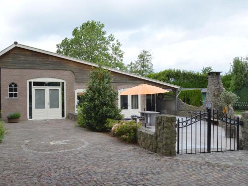 OlstCozy Holiday Home in Olst Wijhe with swimming pool的砖屋,带雨伞和庭院