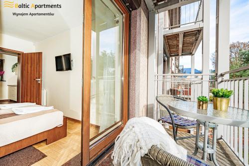 斯维诺乌伊希切Baltic Apartments - Hotelik Przy Promenadzie的客房设有带一张床和一张桌子的阳台。