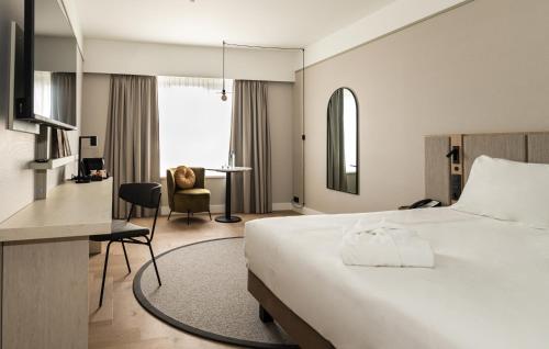 列日Mercure Liege City Centre的配有一张床和一张书桌的酒店客房