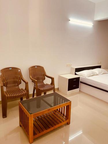 特里凡得琅Amalas Lodge的一间设有两把椅子、一张床和一张桌子的房间