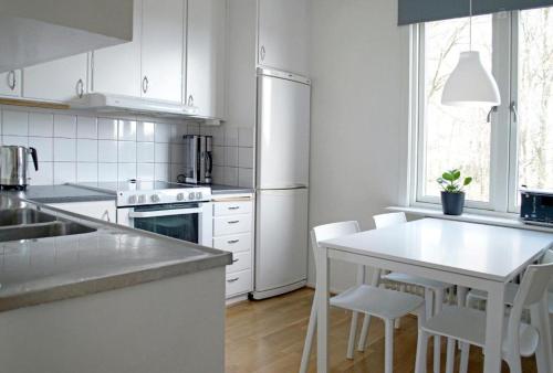 哈尔姆斯塔德Basement Lounge的白色的厨房配有桌子和白色家电