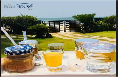比纳里姆Beach House Resort Goa的一张桌子,上面放着两杯,一罐蜂蜜