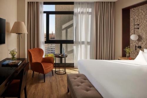 塞维利亚塞维利亚NH酒店集团的酒店的客房 - 带一张床、椅子和窗户
