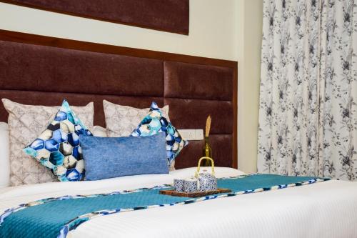 卢迪亚纳Hotel Rawat的一间卧室配有一张带蓝色和白色枕头的床
