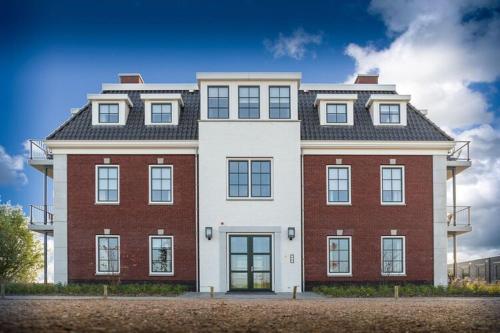 科莱恩斯普拉特Design apartment in Zeeland with its own wellness的街道上一座红色和白色的大建筑
