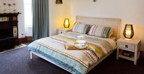 但尼丁阿蒂卡艺术住宿加早餐旅馆的一间卧室配有一张带两张桌子和两盏灯的床。