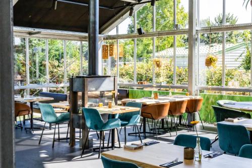 Rijnsburg瓦坎提帕寇宁霍假日公园的餐厅设有桌椅和窗户。