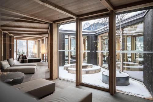 奥蒂塞伊Adler Spa Resort Dolomiti的客厅设有玻璃窗和沙发
