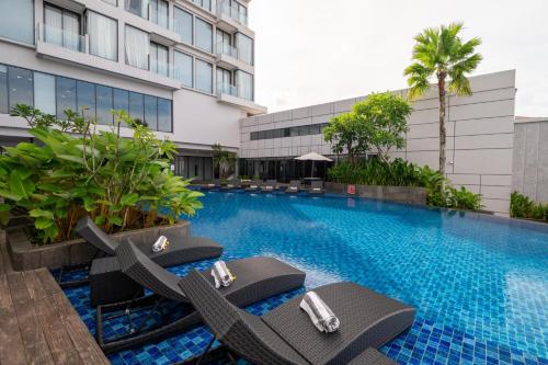 索龙ASTON Sorong Hotel & Conference Center的一座带躺椅的游泳池位于大楼旁