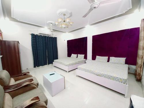 卡拉奇Rose Palace Millennium的紫色窗帘间内的两张床