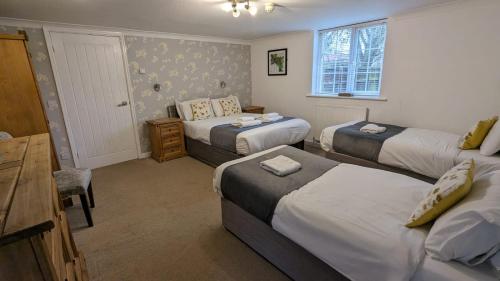 斯卡伯勒East Ayton Lodge Hotel, Scarborough的一间卧室配有三张床、一张桌子和一张桌子