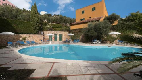 菲纳莱利古雷Italianway - Il Borgo apartments的一座带椅子和遮阳伞的游泳池位于一座建筑旁边