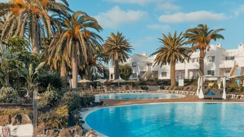 科拉雷侯拉布兰达科拉莱霍村酒店的一座棕榈树和建筑游泳池