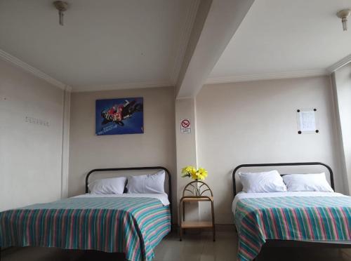 昆卡Hospedaje Fenix的卧室配有两张床,墙上挂着一幅画