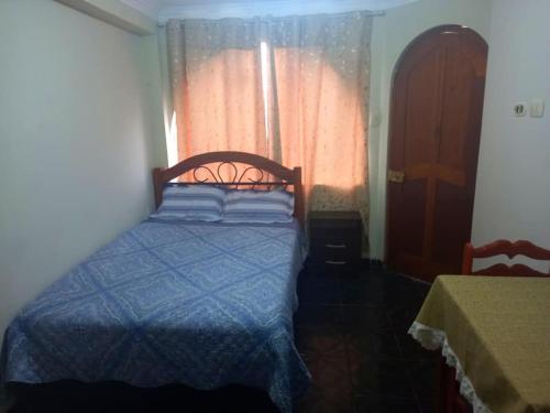 皮斯科Posada de Mary的一间卧室配有一张带蓝色棉被的床和窗户。