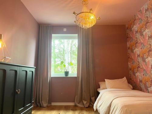 斯德哥尔摩Luxury Villa with Jacuzzi的一间卧室设有一张床、一个窗户和一个吊灯。
