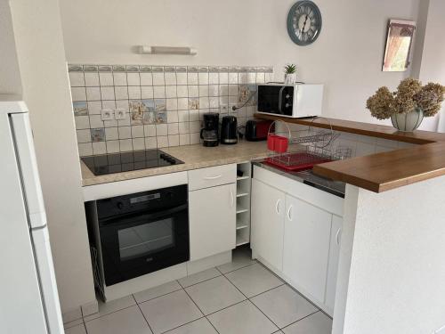 LʼIsle-Saint-CastAppartement T3 Duplex Saint Cast Le Guildo的厨房配有白色橱柜和炉灶烤箱。
