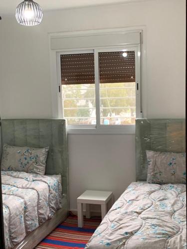 丹吉尔cozy appartement meublé的一间卧室设有两张床和窗户。