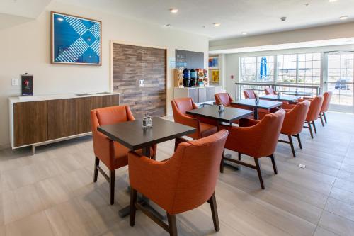 恩格尔伍德Holiday Inn Express & Suites Englewood - Denver South, an IHG Hotel的用餐室配有桌子和橙色椅子