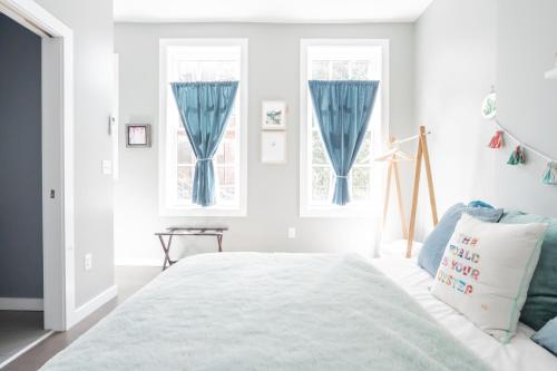 卡温顿Pastel Paradise - Adorable Covington Apartment的白色卧室配有蓝色窗帘和床