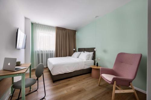 Giv‘atayimSirkin 16 Hotel - Autonomous hotel的酒店客房配有一张床、一张桌子和一把椅子。