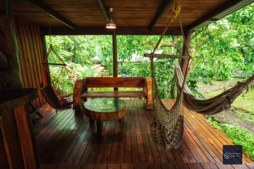 比加瓜Cataratas Bijagua Lodge, incluye tour autoguiado Bijagua Waterfalls Hike的门廊配有吊床、桌子和秋千