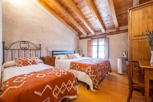 托雷瓦尔德圣佩德Casa Pinines的卧室设有2张床,铺有木地板,设有天花板