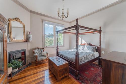 DerbyDerby Bank House- Heritage listed two bedroom old school B&B suite or a self contained cabin的一间卧室设有一张天蓬床和一个壁炉