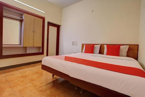 马杜赖OYO Hotel Radhakrishna的一间卧室配有一张带红色枕头的大床