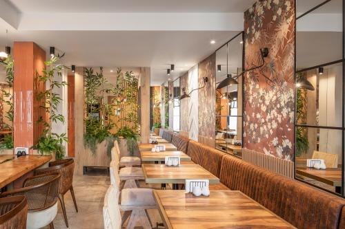 蒂米什瓦拉Hotel Branco Timisoara的餐厅设有木桌和椅子,种有植物