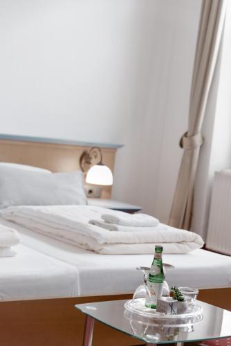 Reichshof Hotel Barbarossa的一间卧室配有一张床和一张桌子,上面装有一瓶