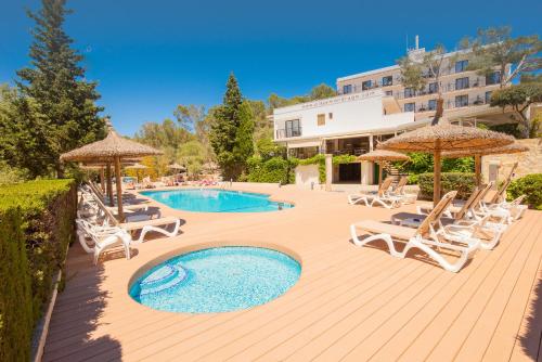 波多佩特罗Hotel Playa Mondrago的木制甲板上配有椅子和遮阳伞的游泳池