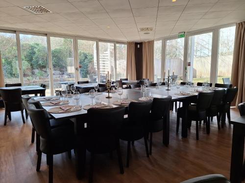 哈尔姆斯塔德Hotell Toftalund的大型用餐室设有桌椅和窗户。